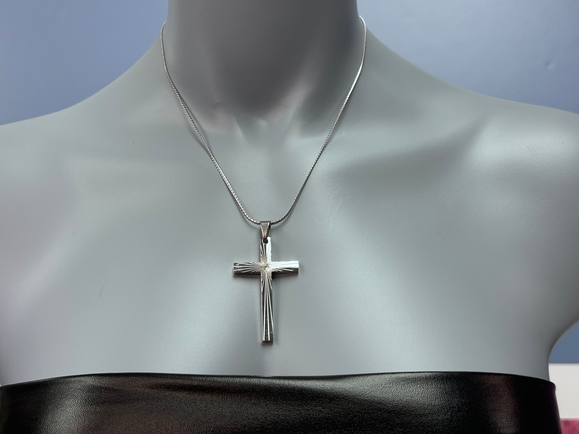 Minimalist religious necklace against a neutral background
