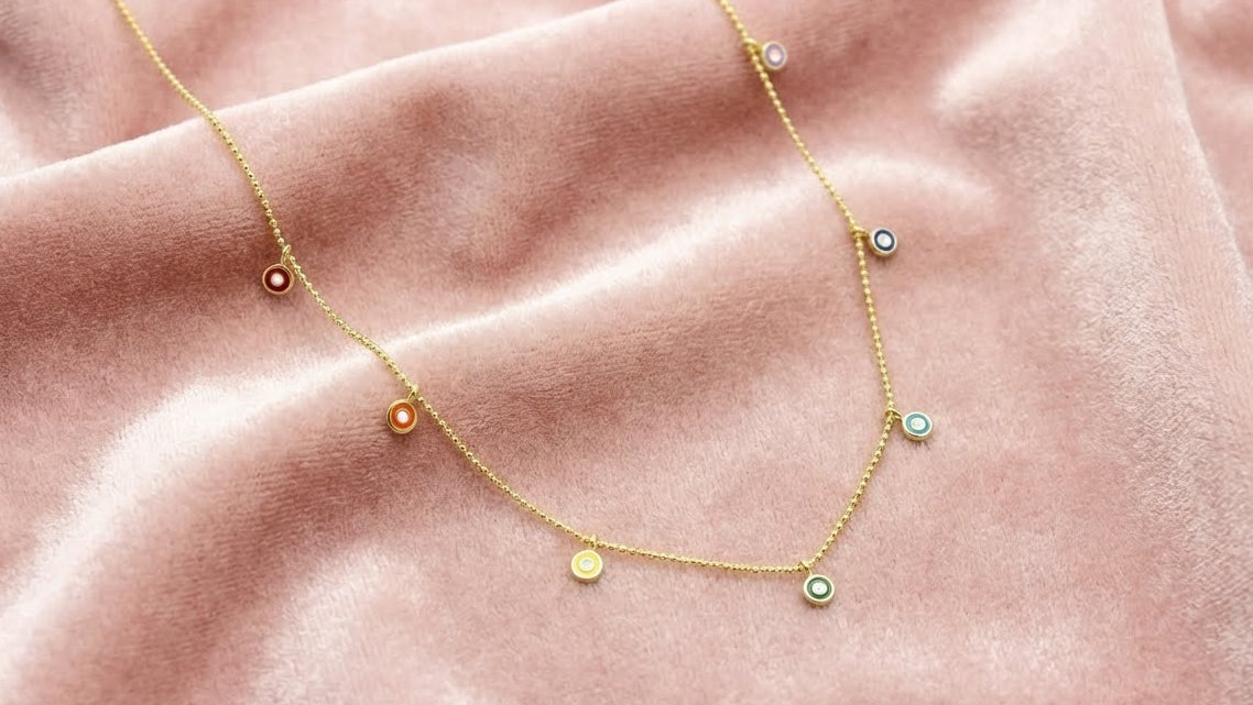 Gold necklace with small round pendants on a pink fabric background